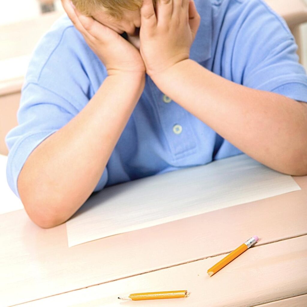 frustrated 3rd grade boy with blank paper and broken pencil