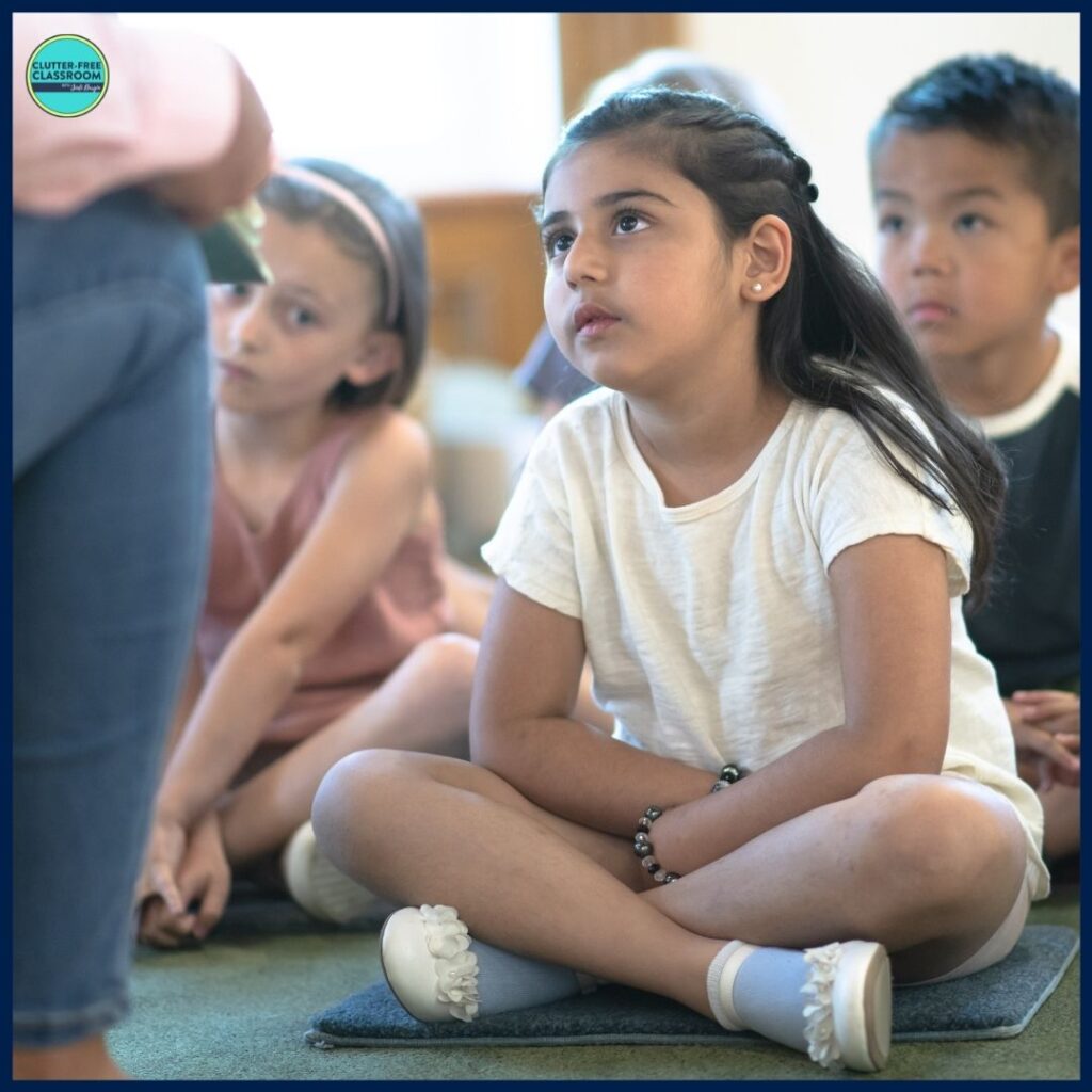 elementary students sitting on rug spots listening to a picture book being read aloud