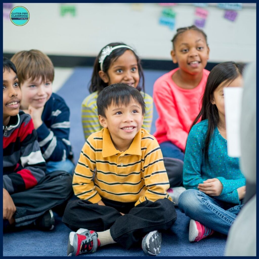 six students sitting on the rug listening to a picture book being read aloud by their teacher