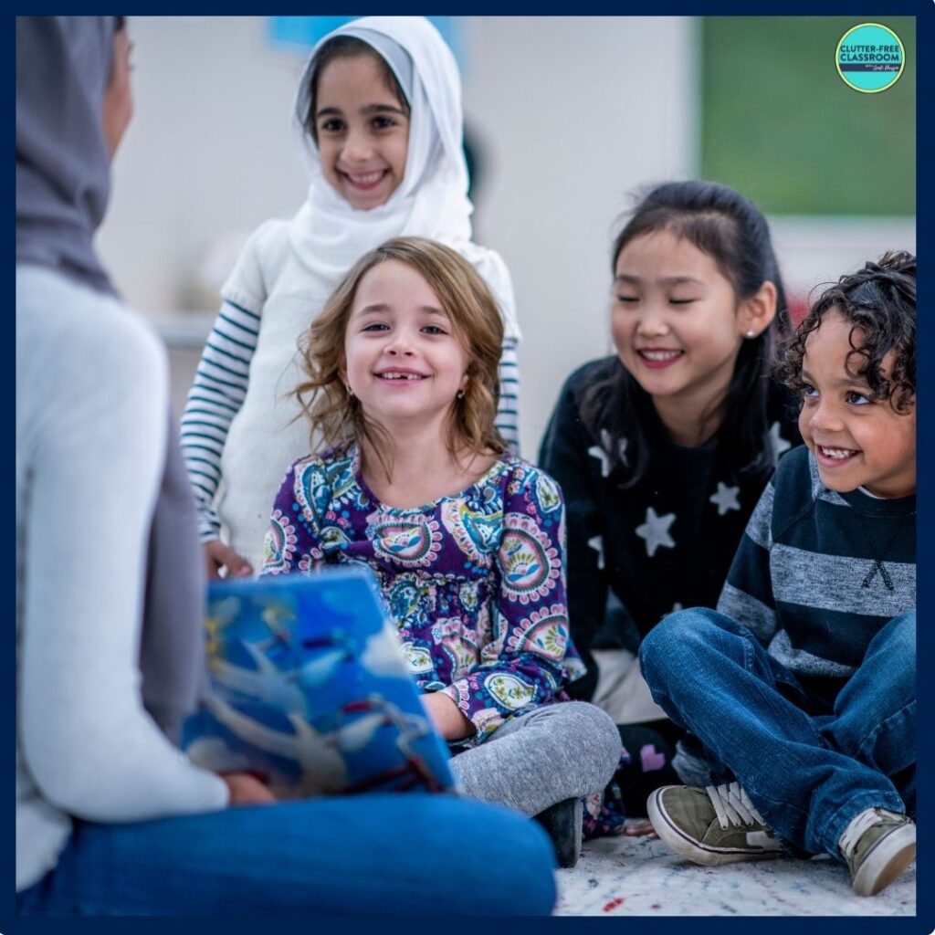 elementary students sitting on the rug listening to a picture book being read aloud by their teacher